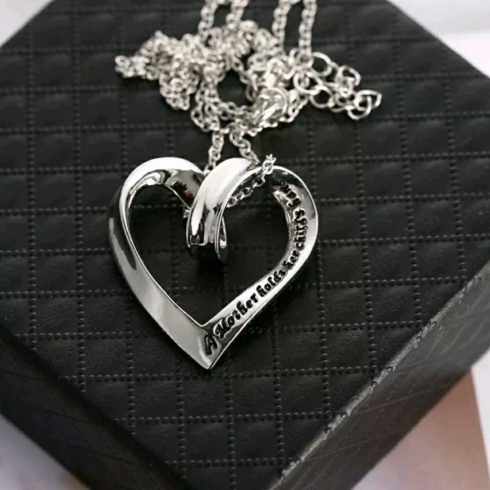 "A mother holds her child's hand for a moment... silver heart necklace.